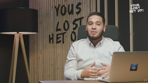 Vlogger YousToub zit aan een bureau achter een laptop